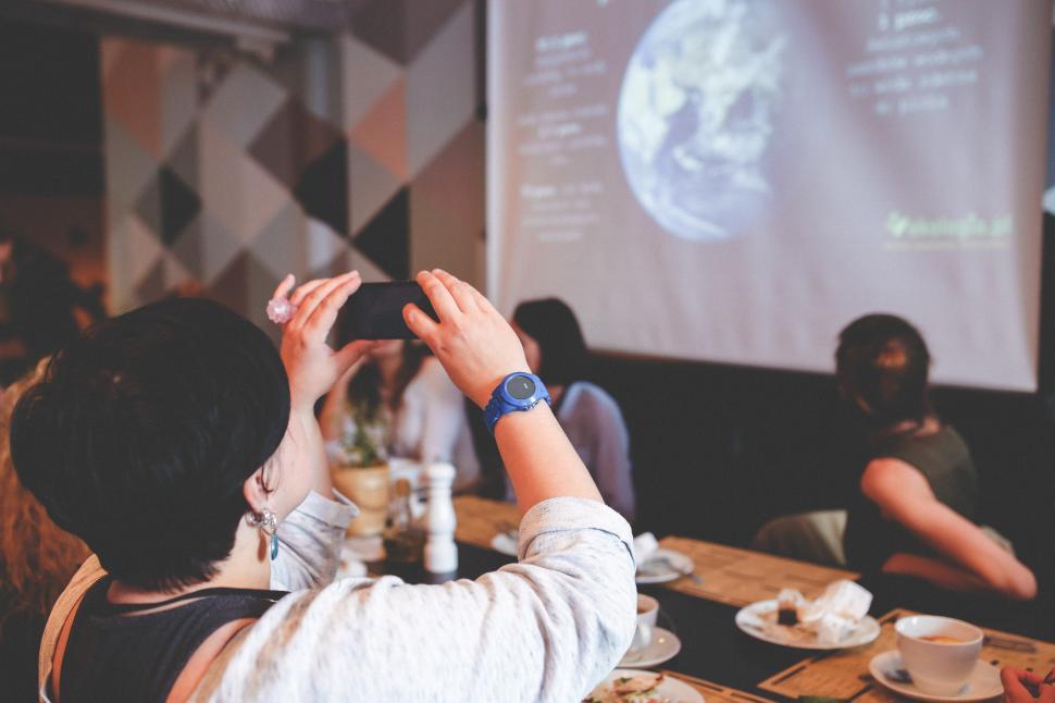 Free Image of Group of People Sitting at Table in Front of Projector Screen 