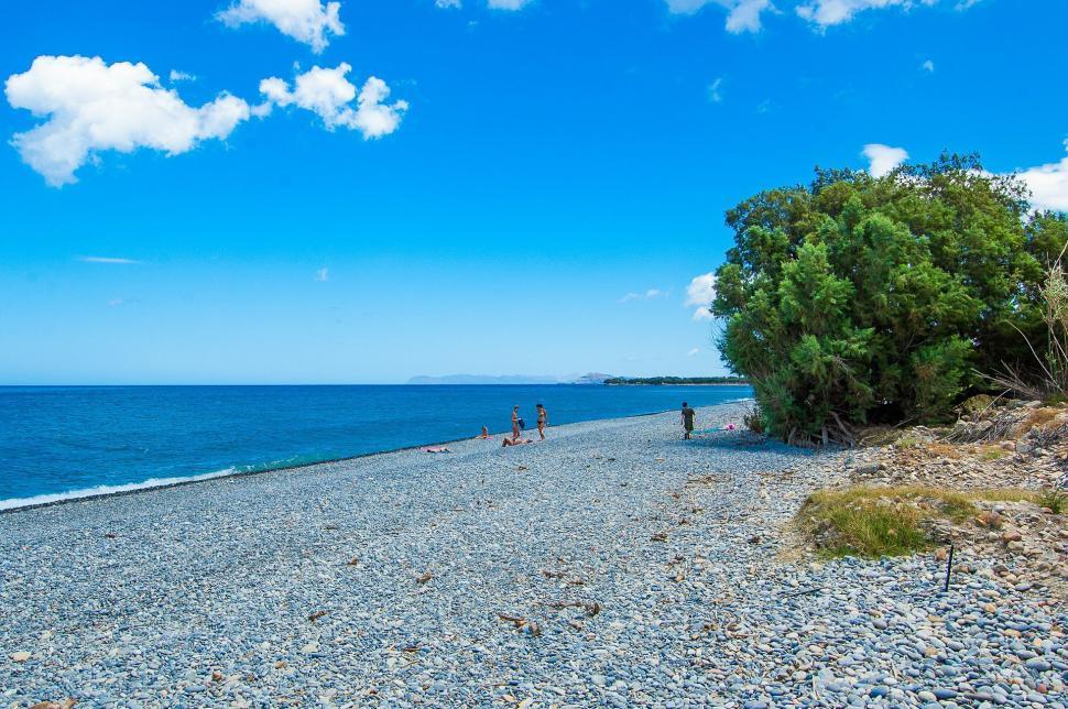 Free Image of People Walking on Rocky Beach Near Ocean 