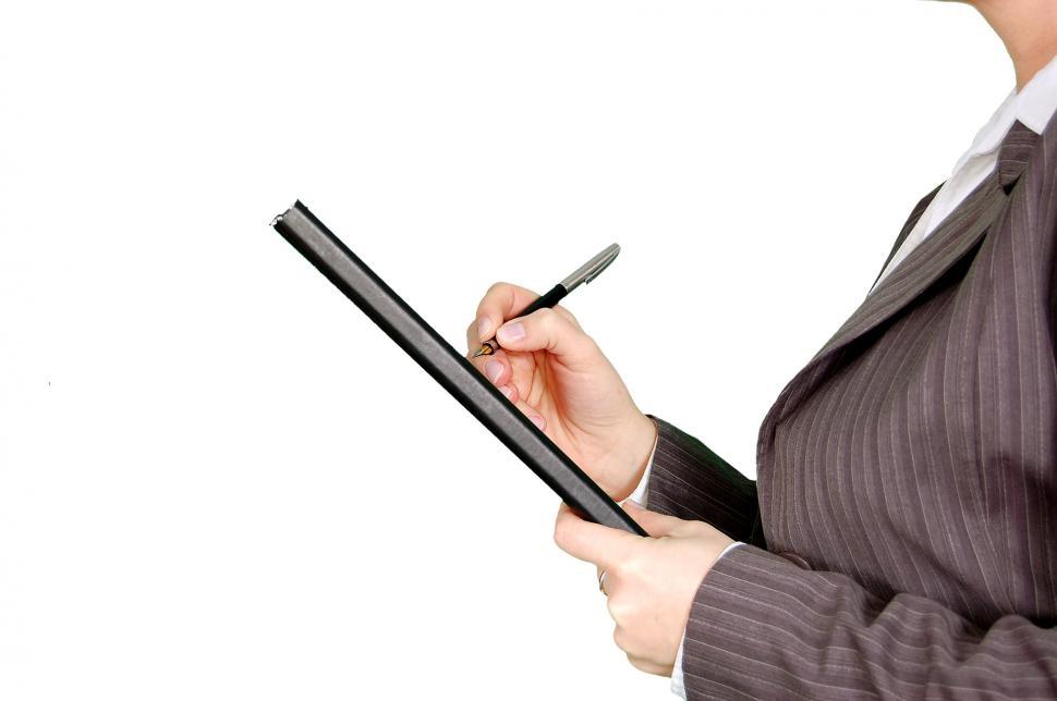 Free Image of Woman in Business Suit Writing on Clipboard 