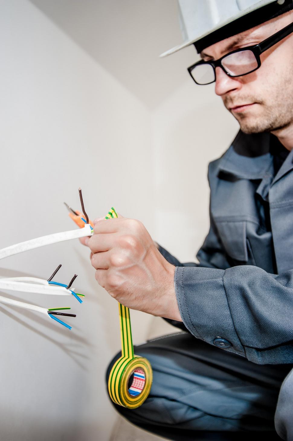 Free Image of Man in Hard Hat Holding Pair of Scissors 