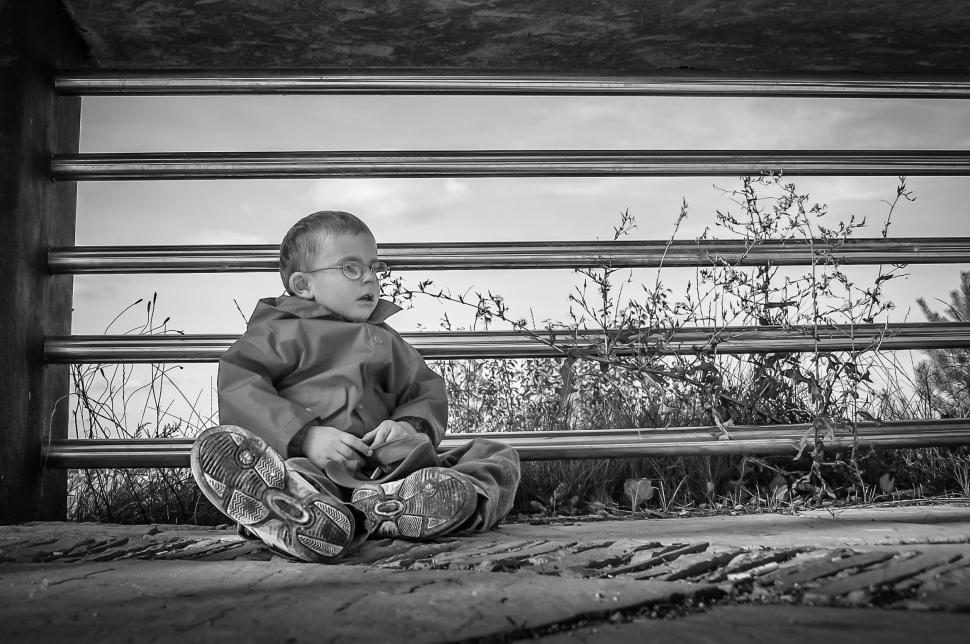 Free Image of Young Boy Sitting in Front of Fence 