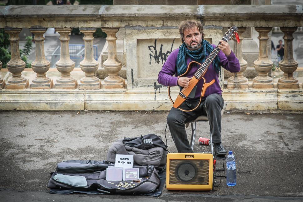 Free Image of Man Sitting on Box Beside Guitar 