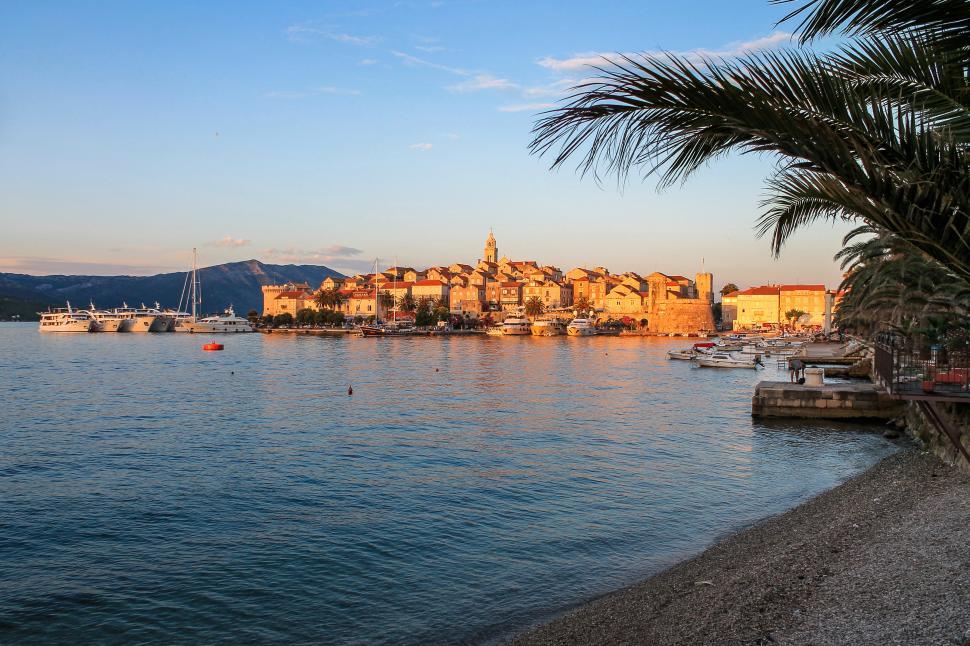 Free Image of Medieval Town at Sunset with Palm Trees and Beach  