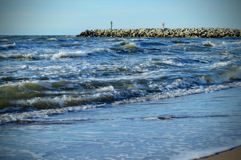Free Image of Baltic Sea coast with waves and a breakwater of rocks in the background 