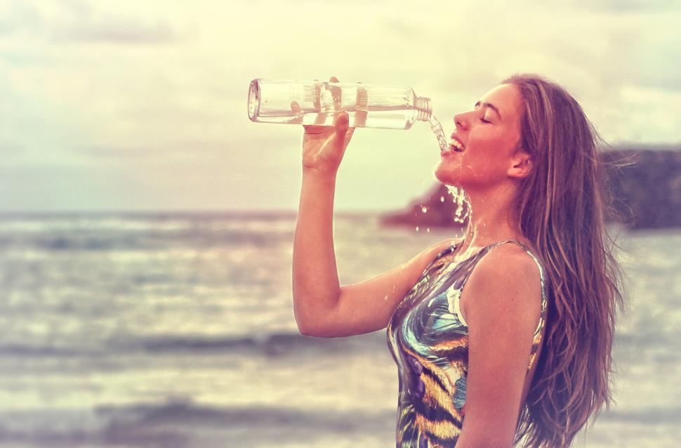 Free Image of Young Woman Drinking Sparkling Water at the Beach - Health and F 