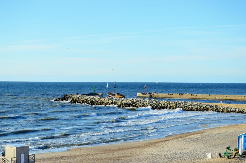 Free Image of The ship enters the bay bounded by two stone breakwaters 