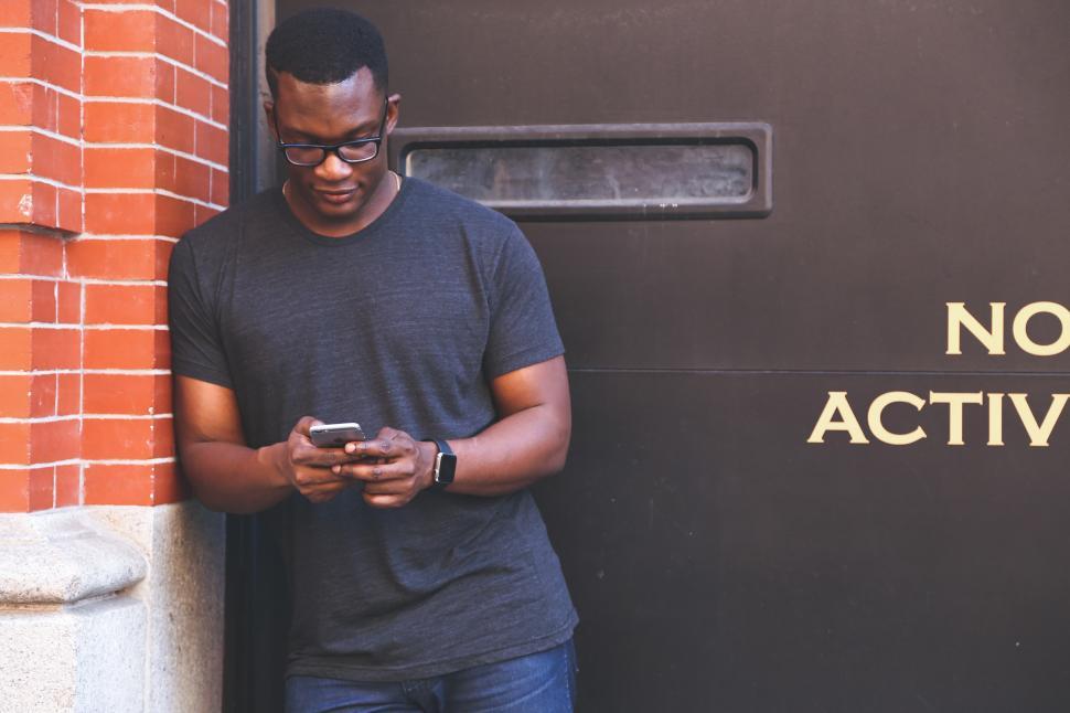 Free Image of Leaning against a wall on smart phone 