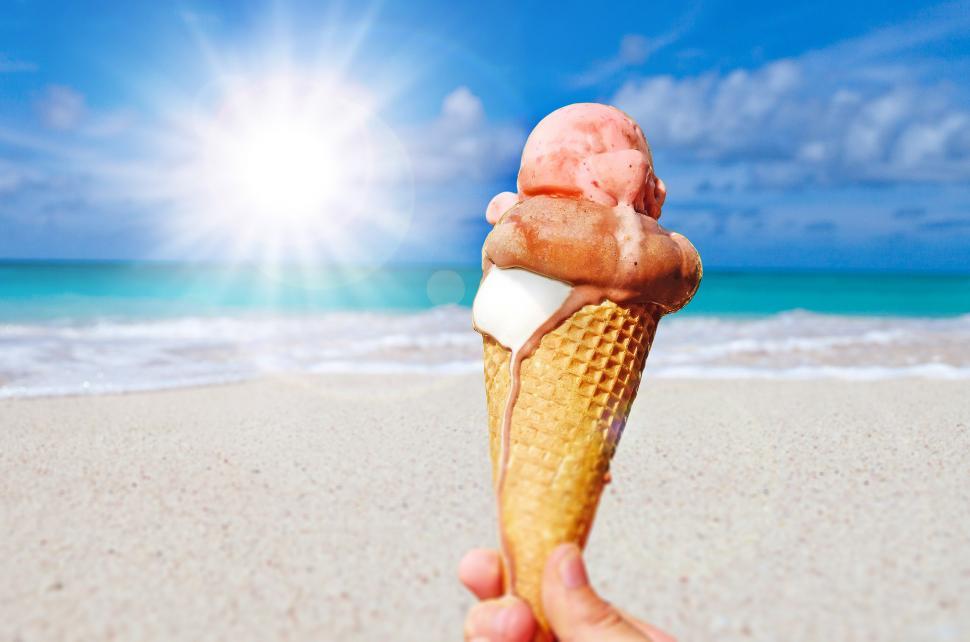 Free Image of Hand Holding Ice Cream Cone on Beach 