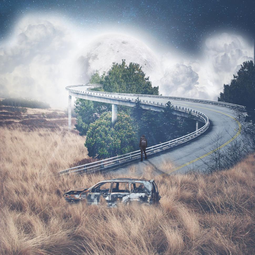 Free Image of Car Driving on Road With Bridge in Background 