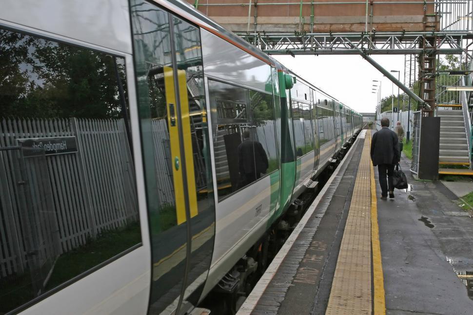Free Image of Man Walking Next to a Train With Suitcase 