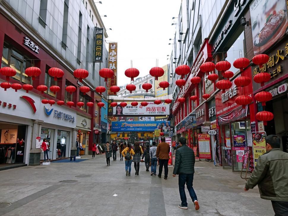 Free Image of Group of People Walking Down Street Next to Tall Buildings 