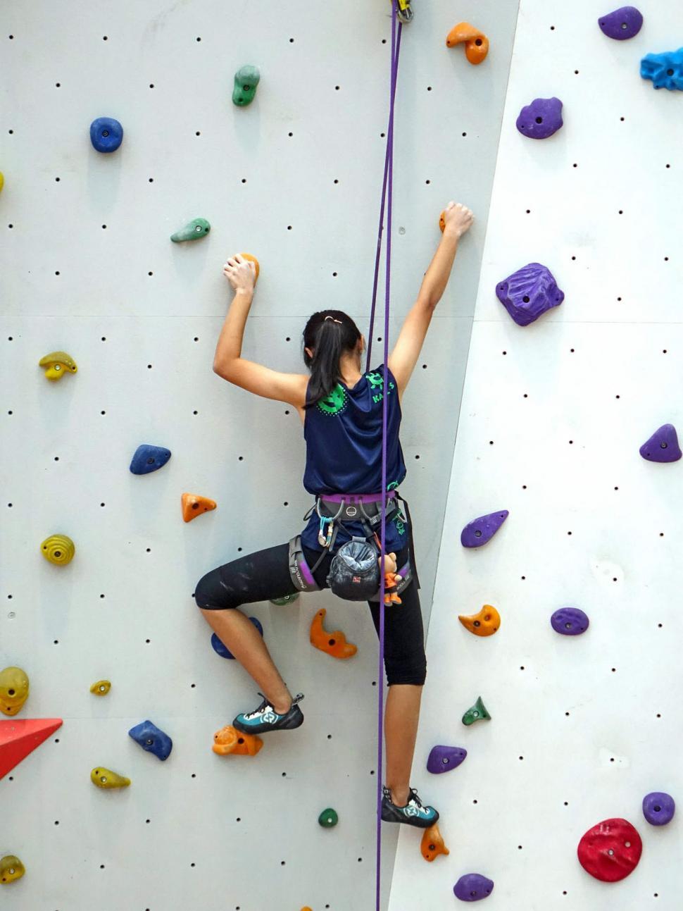 Free Image of Woman Climbing Up the Side of a Climbing Wall 