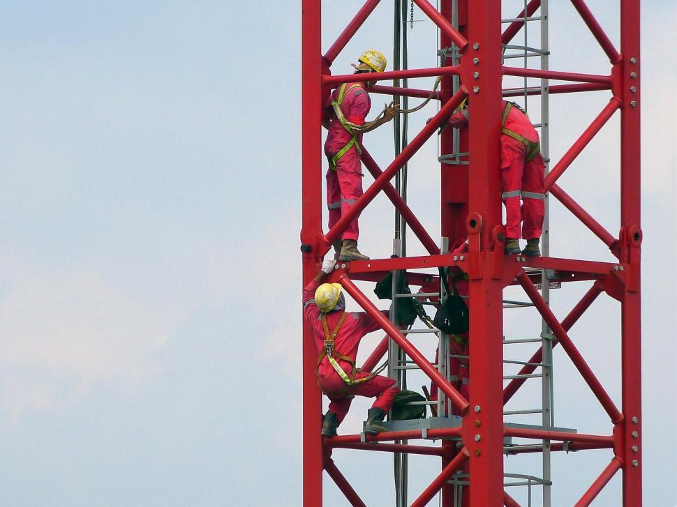 Free Image of Group of Men Standing on Top of a Red Tower 