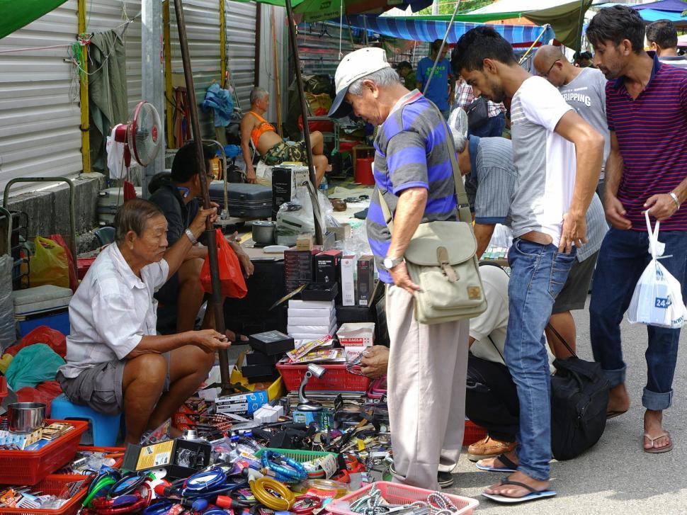 Free Image of Group of People Standing Around Pile of Items 