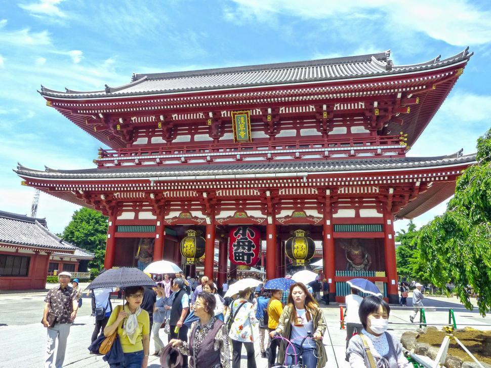 Free Image of Group of People With Umbrellas Walking in Front of a Building 