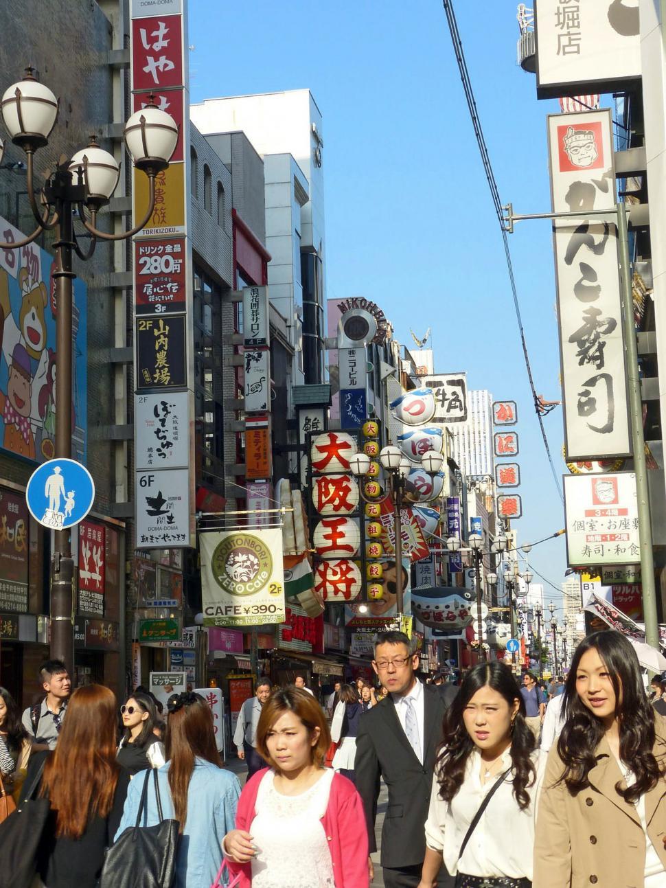 Free Image of Group of People Walking Down Street Next to Tall Buildings 
