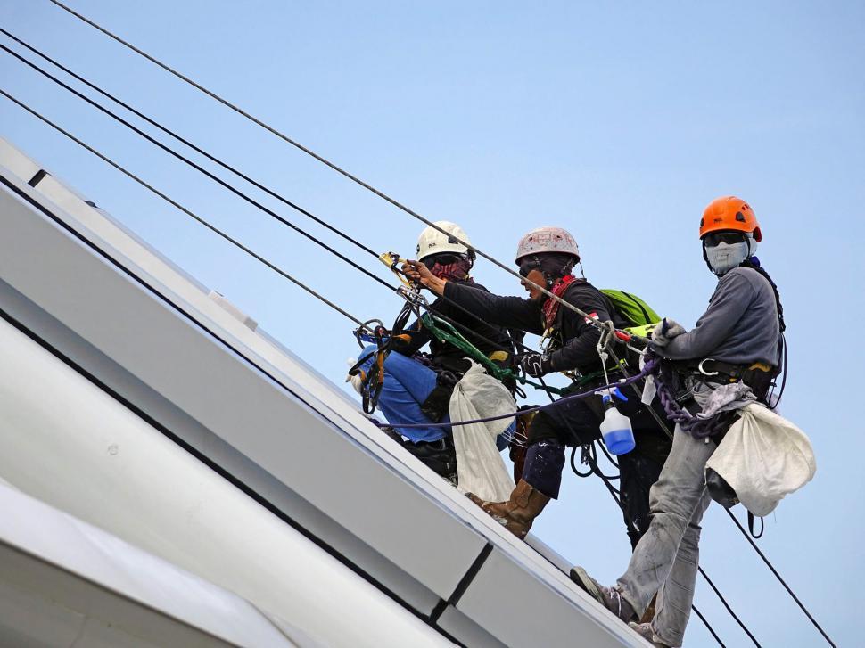 Free Image of Men Standing on Top of a Power Line 