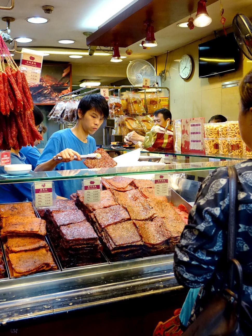 Free Image of Man Standing in Front of Food Display 