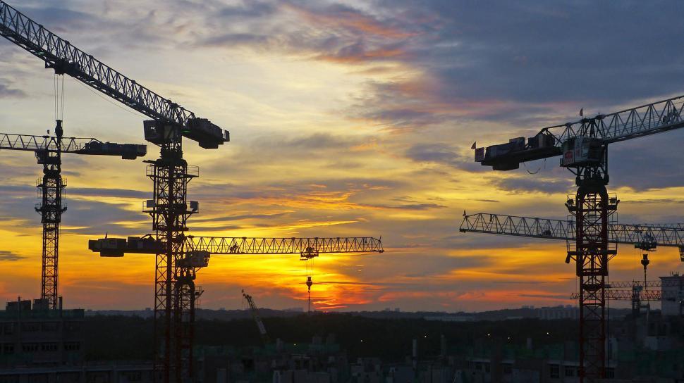 Free Image of Group of Cranes Perched on Building Under Cloudy Sky 