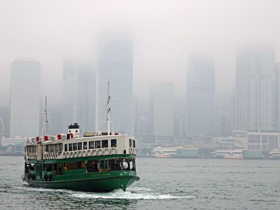 Free Image of Green and White Boat Sailing on a Large Body of Water 