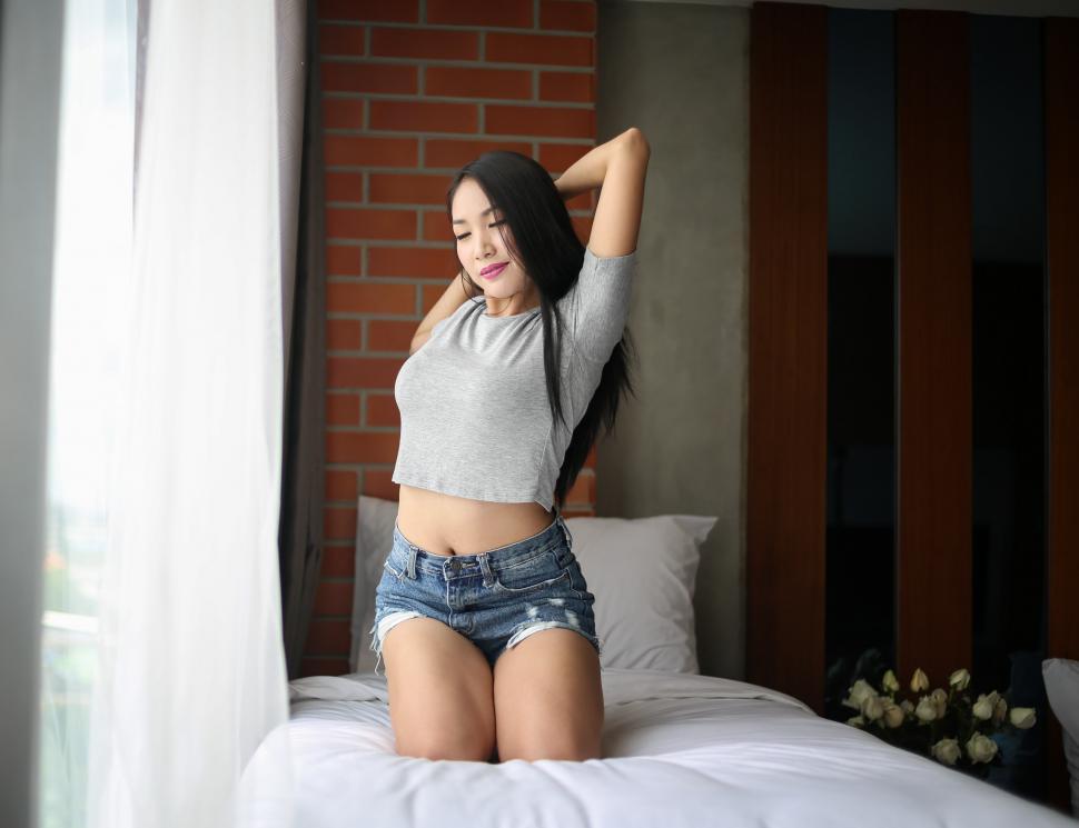 Free Image of Woman Sitting on Bed Next to Window 