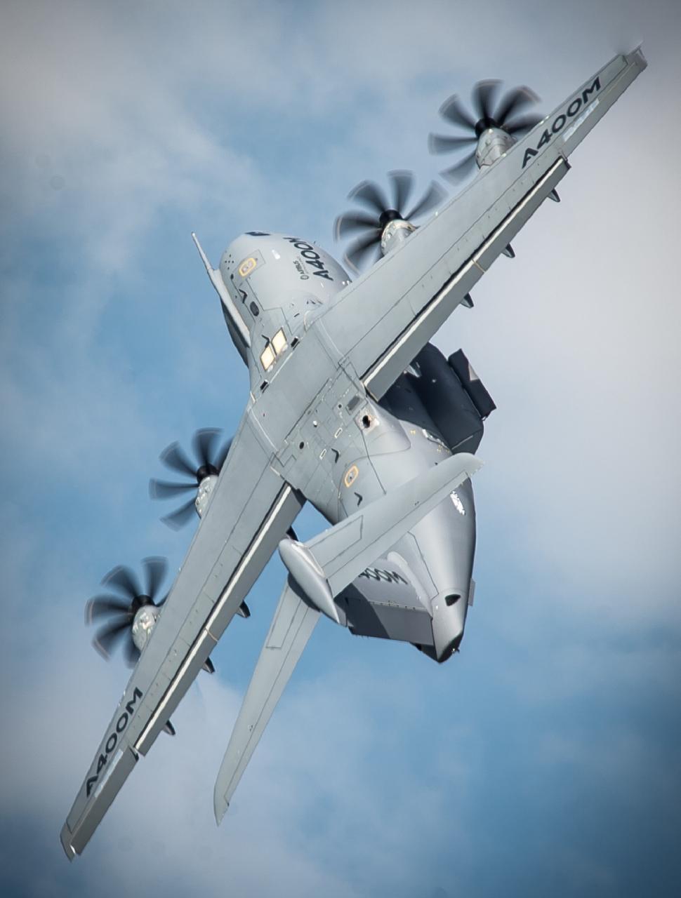 Free Image of Large Propeller Plane Flying Through Cloudy Blue Sky 