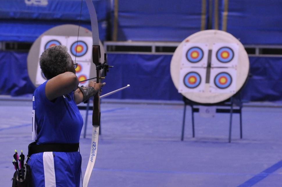 Free Image of Man Holding Bow and Arrow in Front of Target 