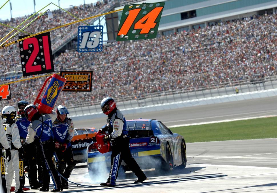 Free Image of Group of People Standing Around Car on Race Track 