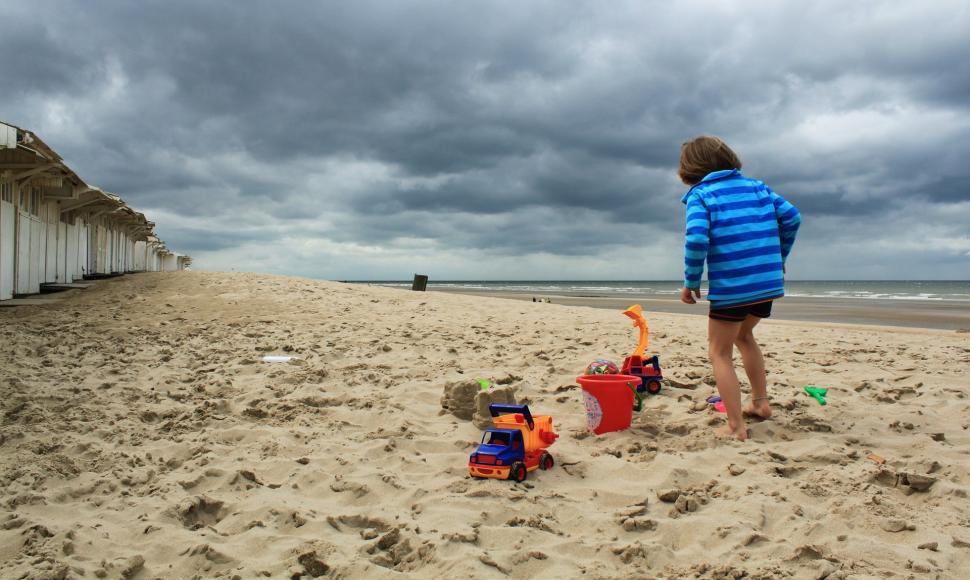 Free Image of Young Boy Standing on Top of Sandy Beach 
