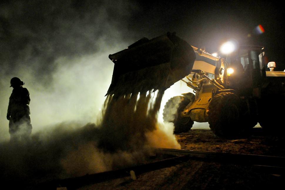 Free Image of Man Standing Next to Bulldozer in the Dark 