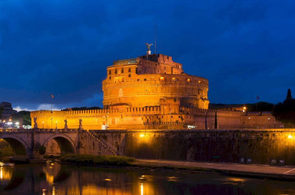 Free Image of Castle Illuminated at Night Beside River 