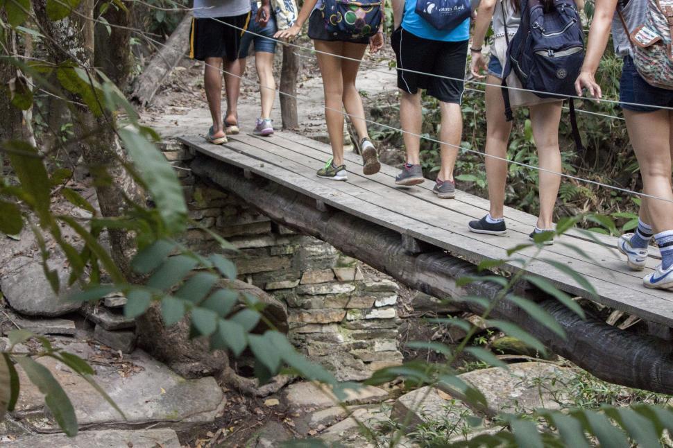 Free Image of Group of People Walking Across Wooden Bridge 