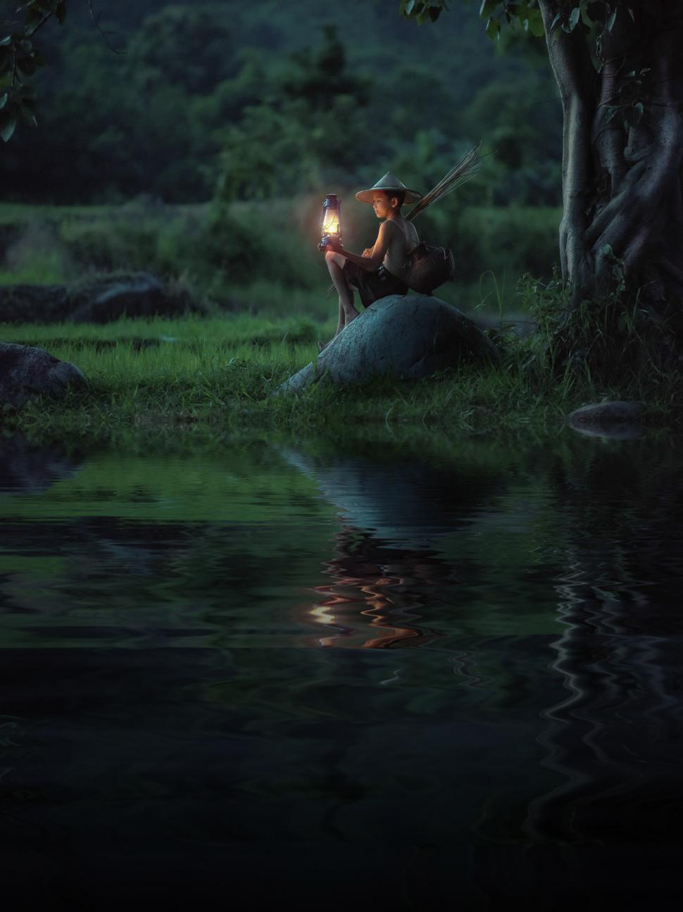 Free Image of Man Sitting on Rock by River 