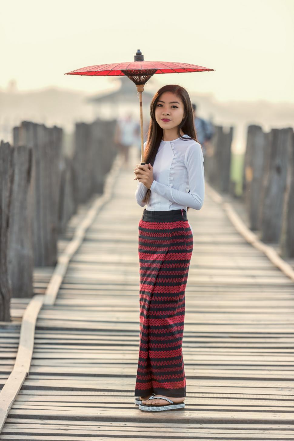 Free Image of Woman Standing on Bridge Holding Umbrella 