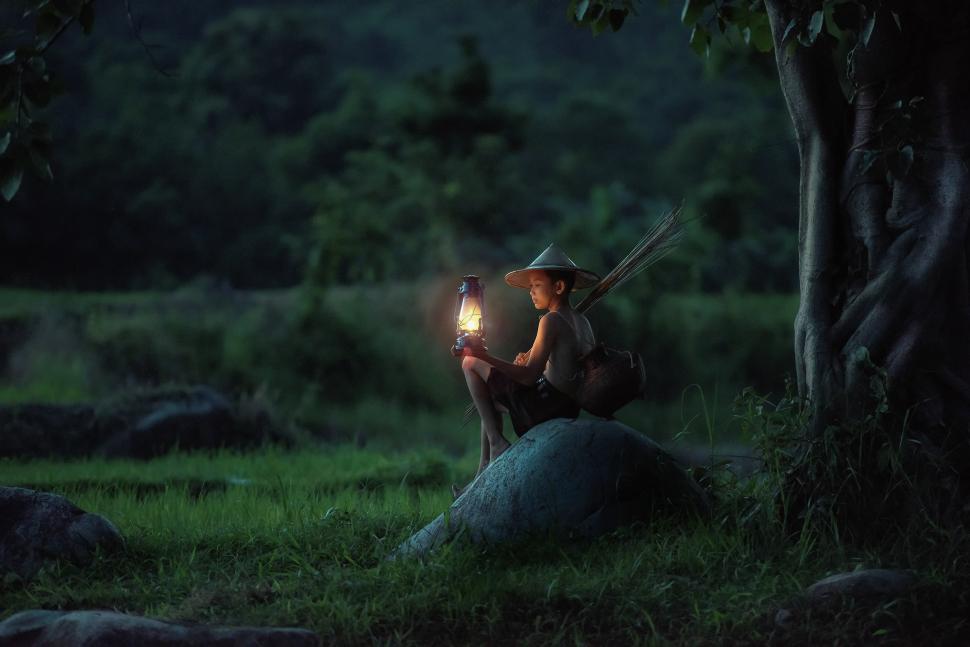 Free Image of Man Sitting on a Rock Holding a Light 