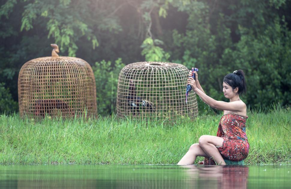 Free Image of Woman in Red Dress Sitting on Rock by Water 
