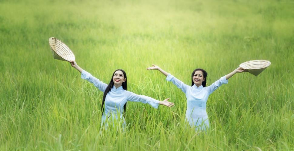 Free Image of Two Women in a Field Holding Tennis Rackets 