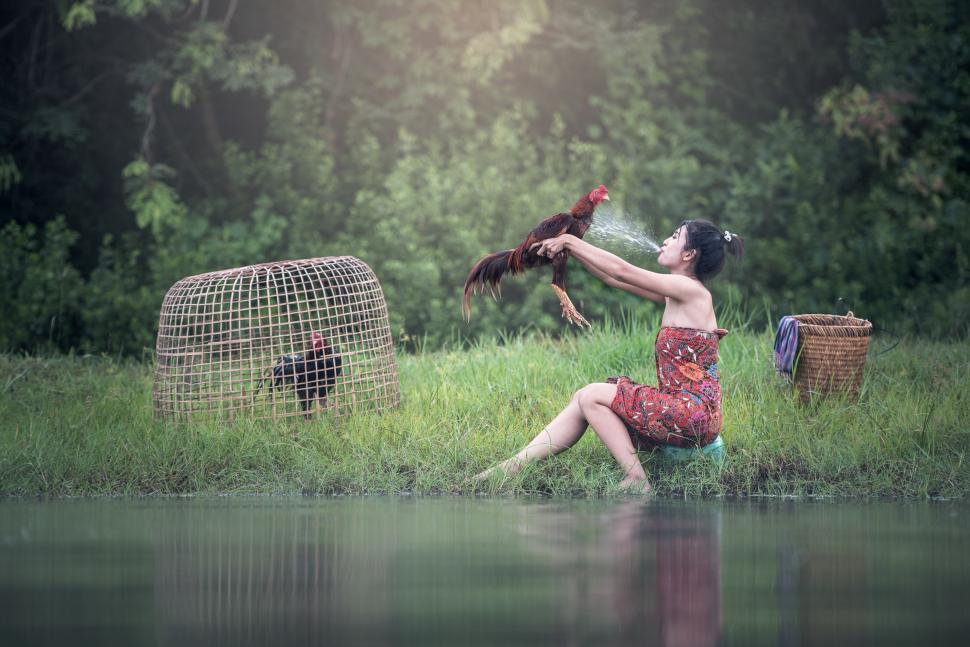Free Image of Woman in Red Dress Sitting on Grass Field Next to Bird Cage 