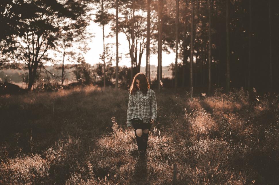 Free Image of Person Walking Through Field With Trees in Background 