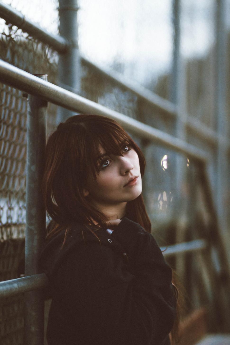 Free Image of Woman Standing Next to Metal Fence 