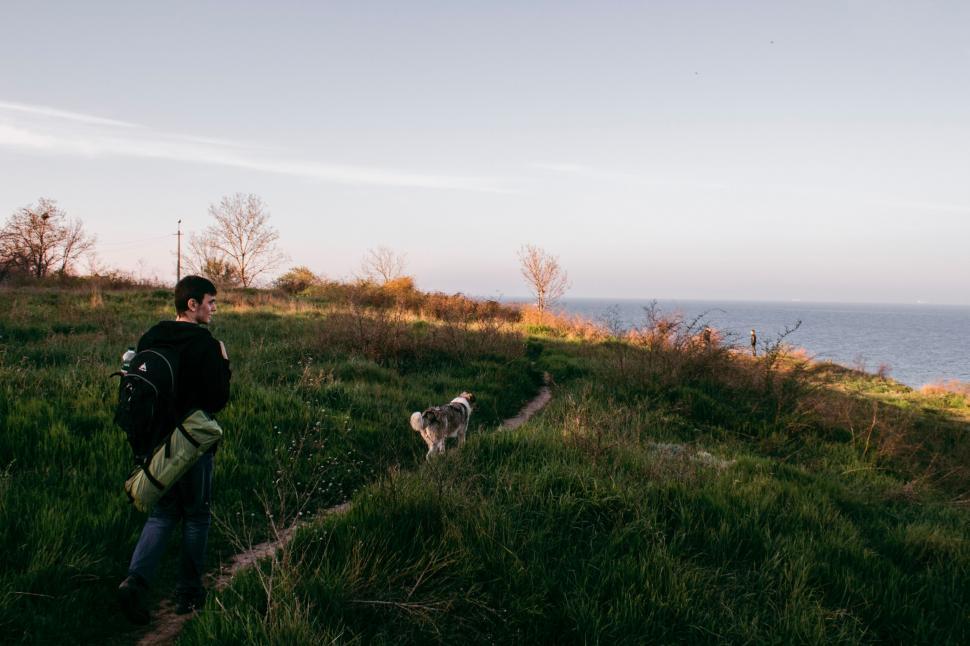 Free Image of Man Walking Down Hill Next to Dog 