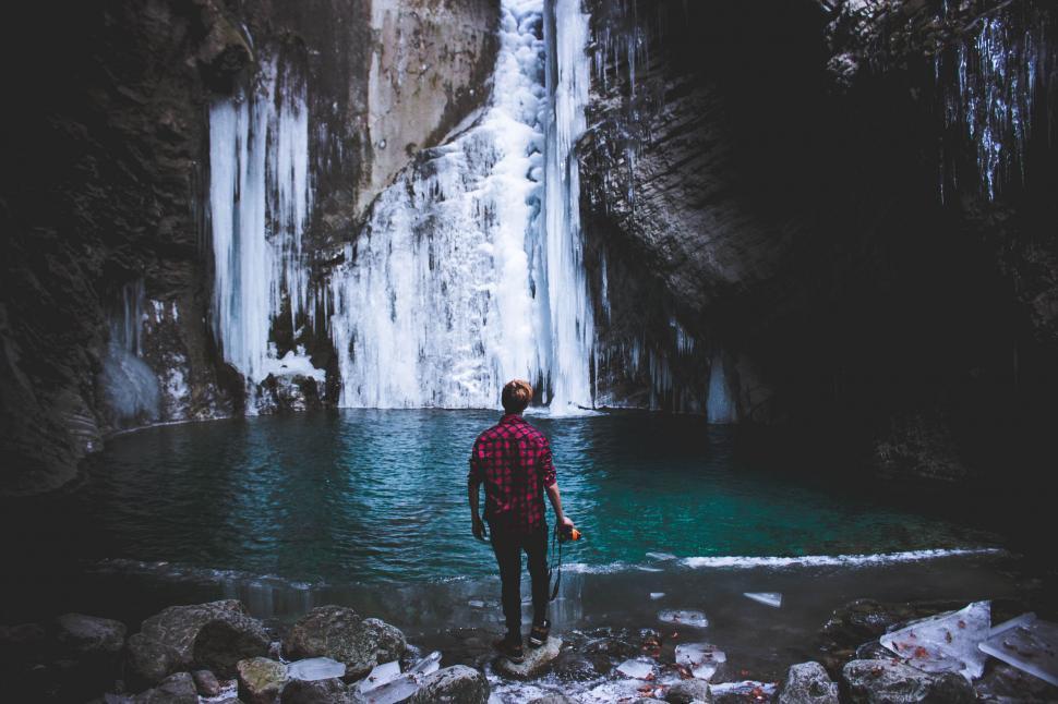 Free Image of Man Standing in Front of a Waterfall 