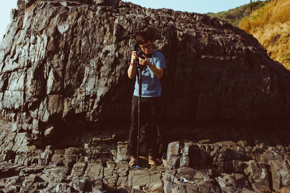 Free Image of Man Taking Picture of Rock Formation 