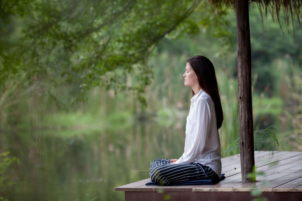 Free Image of Woman Sitting on Dock in White Shirt and Black & White Striped Pants 