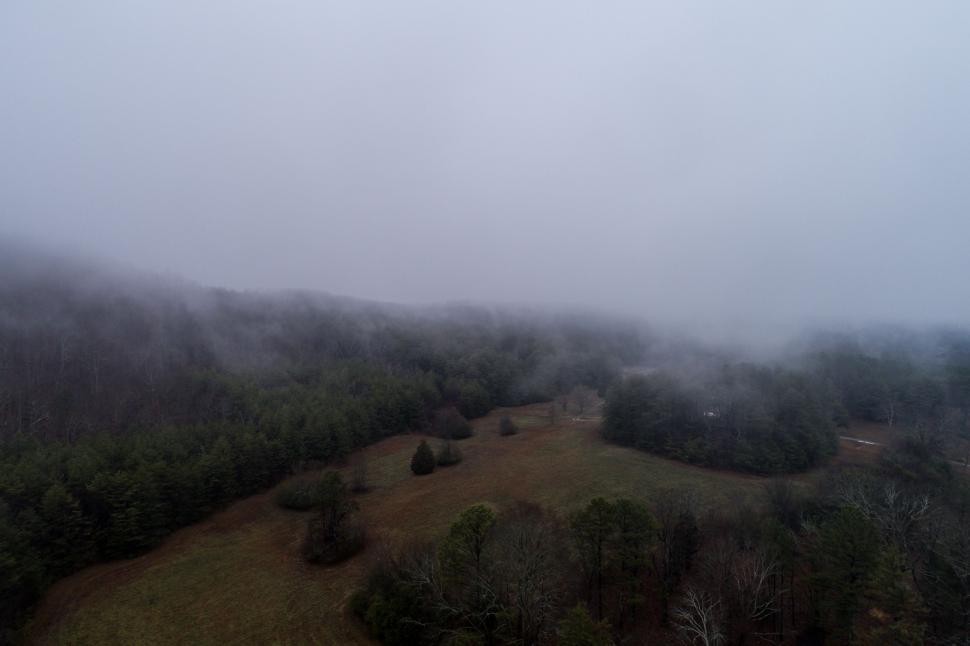 Free Image of Plane Soaring Over Foggy Forest Covered Hillside 