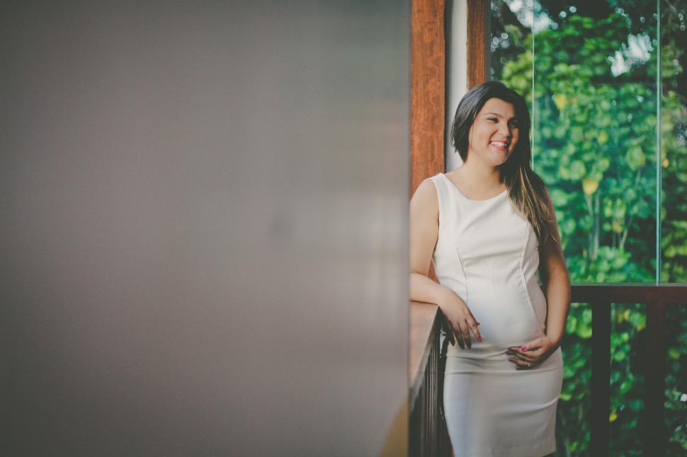Free Image of Pregnant Woman Standing in Front of Window 