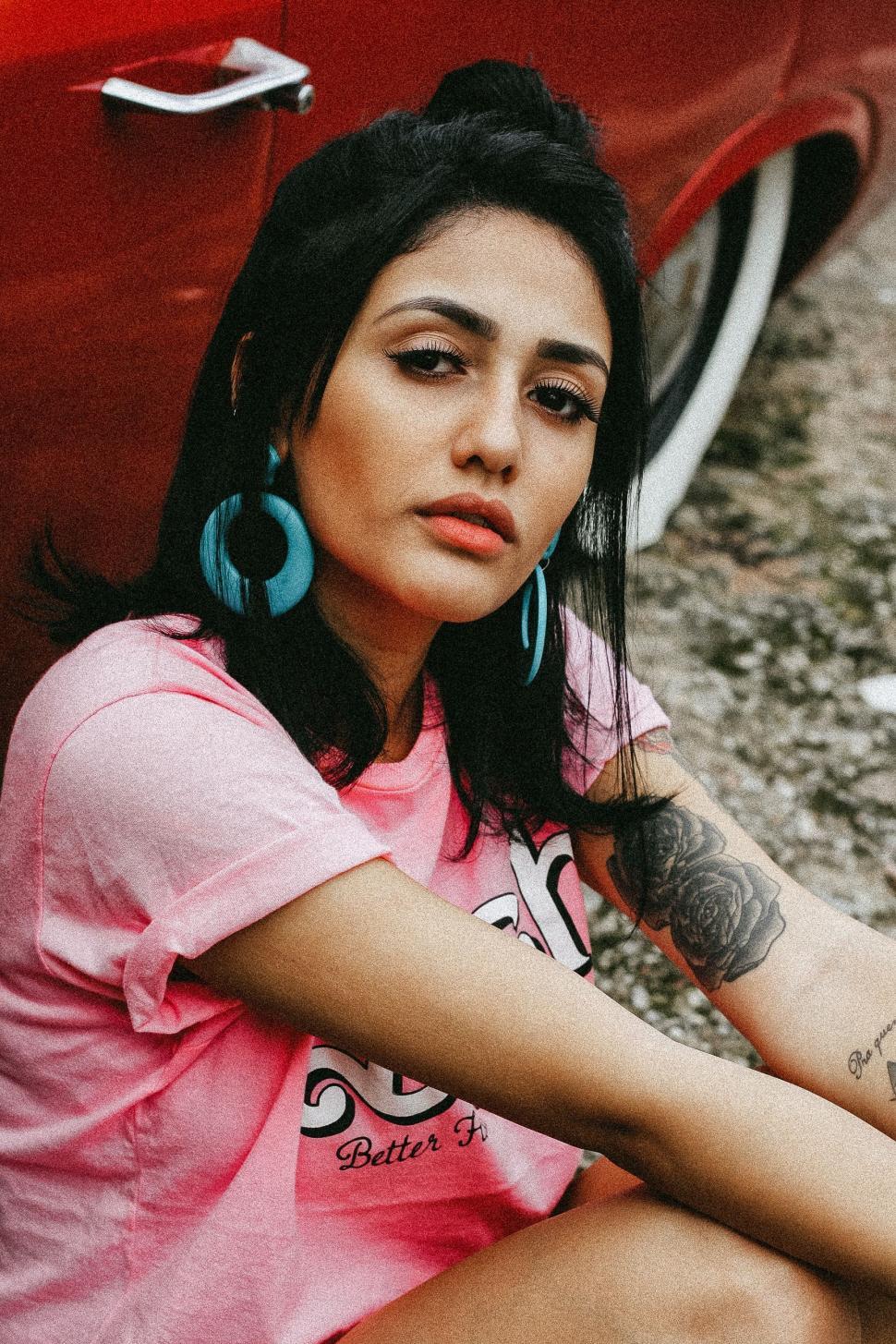 Free Image of Woman Sitting Next to Red Car 