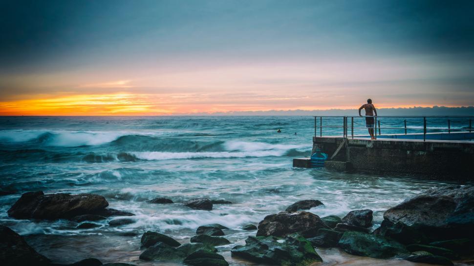 Free Image of Man Standing on Pier by Ocean 