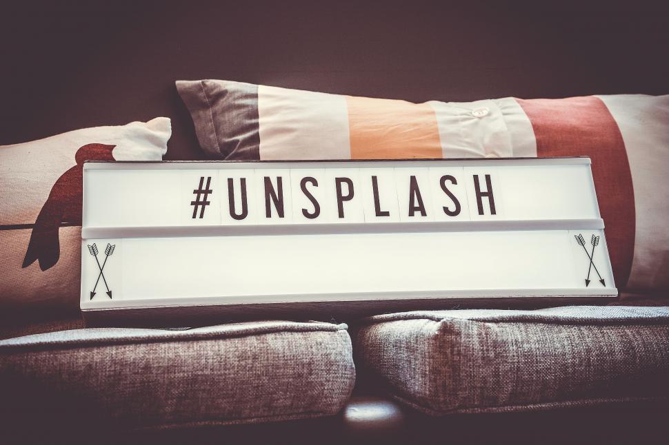 Free Image of Bed With Pillows and Unsplash Sign 