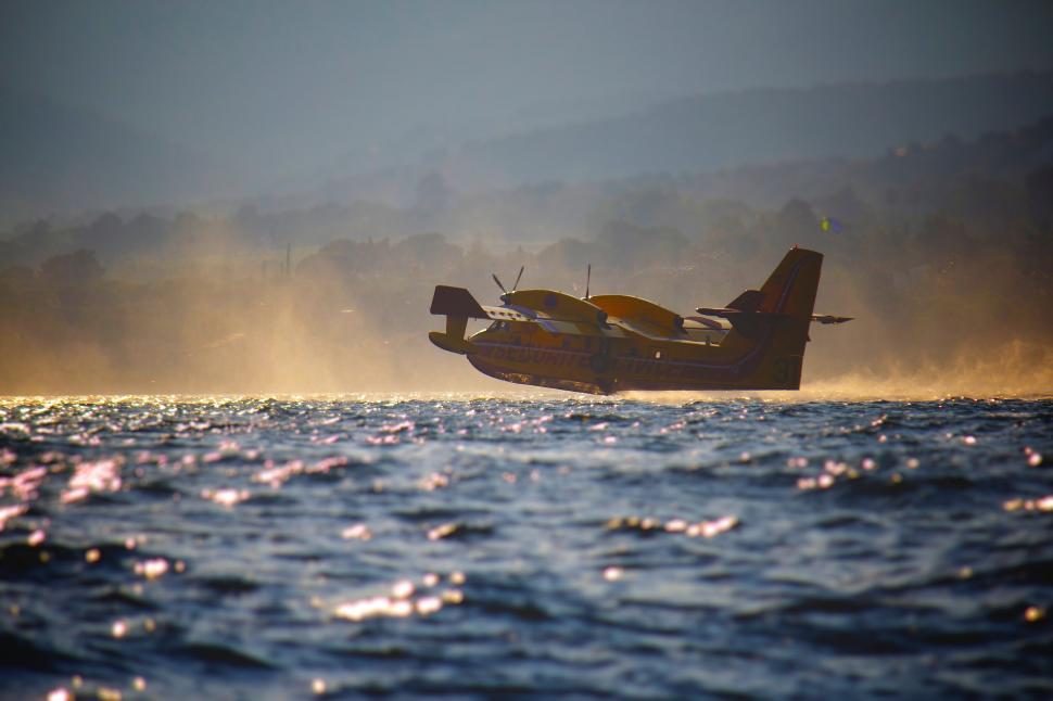 Free Image of Small Plane Flying Over Large Body of Water 